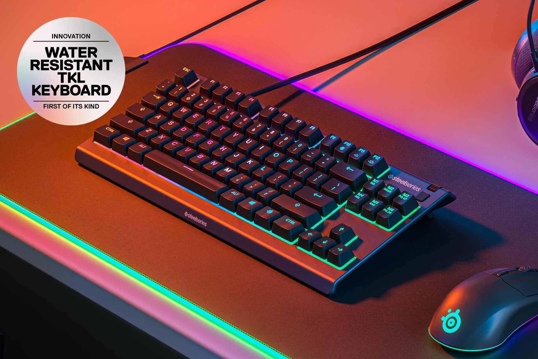 
 Apex 3 TKL keyboard sitting on a mousepad, bathing in a the celestial glow of SteelSeries RGB. Round text box reads: "Innovation: Water resistant TKL Keyboard: First of its kind."
 